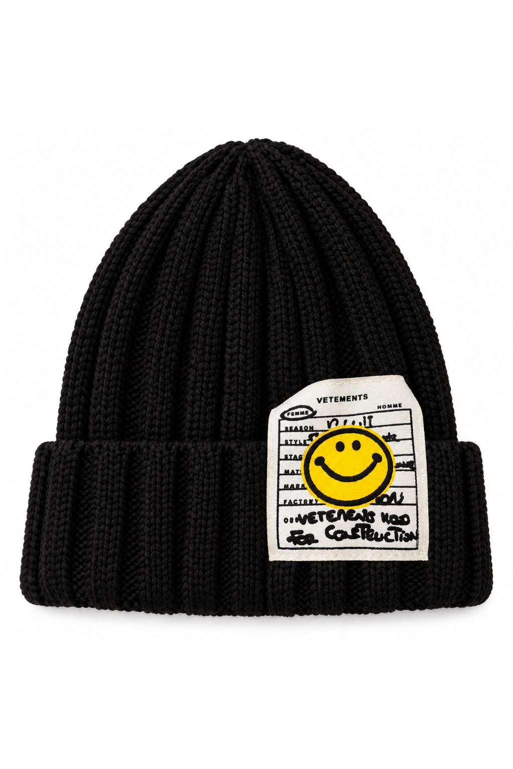 A black ribbed knit beanie hat featuring a white rectangular patch with a yellow smiley face and handwritten-style text, photographed on a plain white background.