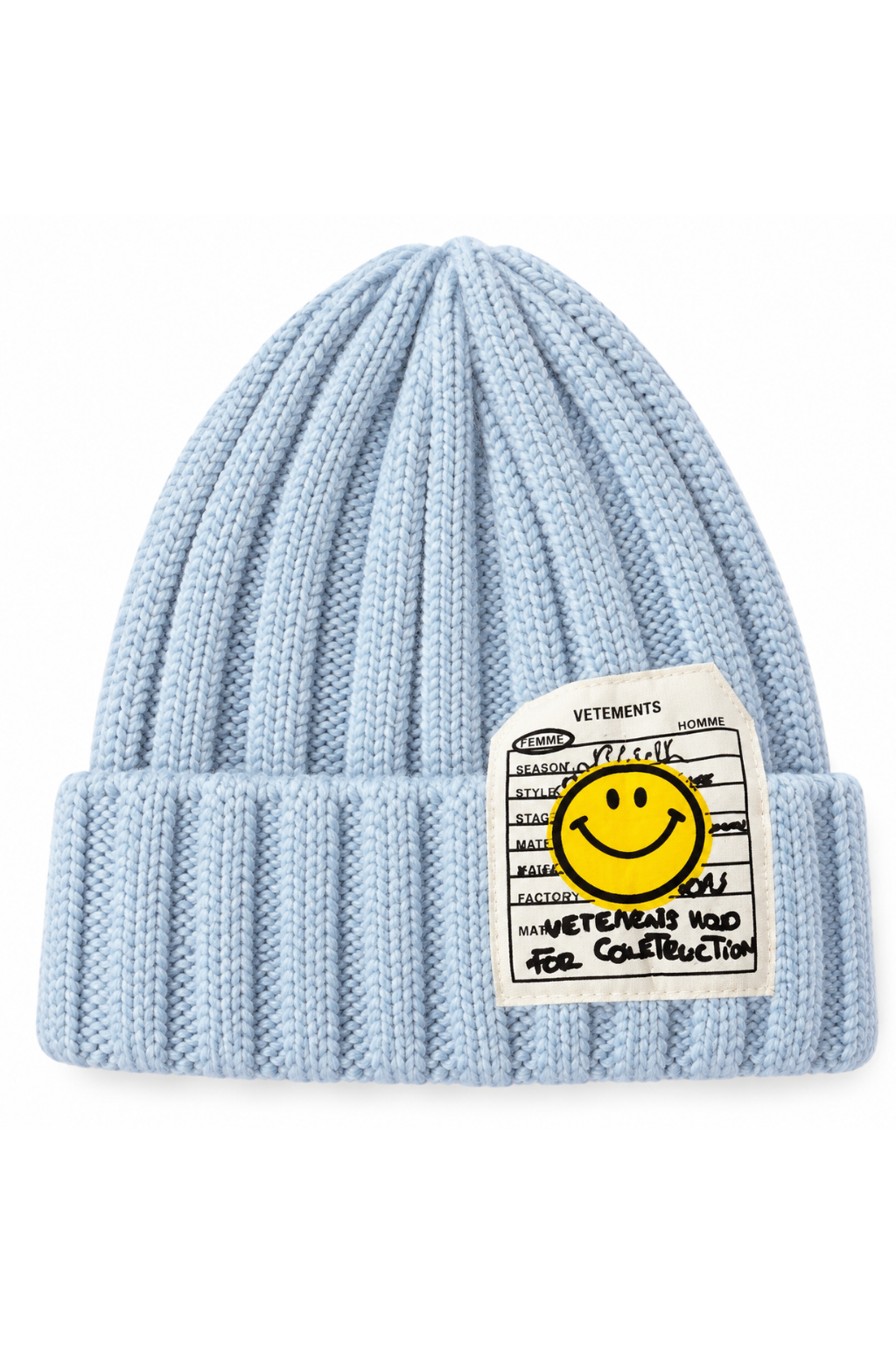 A light blue ribbed knit beanie hat featuring a white rectangular patch on the front with a yellow smiley face and black text, photographed on a clean white background.
