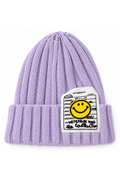 A light purple ribbed knit beanie hat featuring a white rectangular patch with a yellow smiley face and black text, including 'VETEMENTS'.